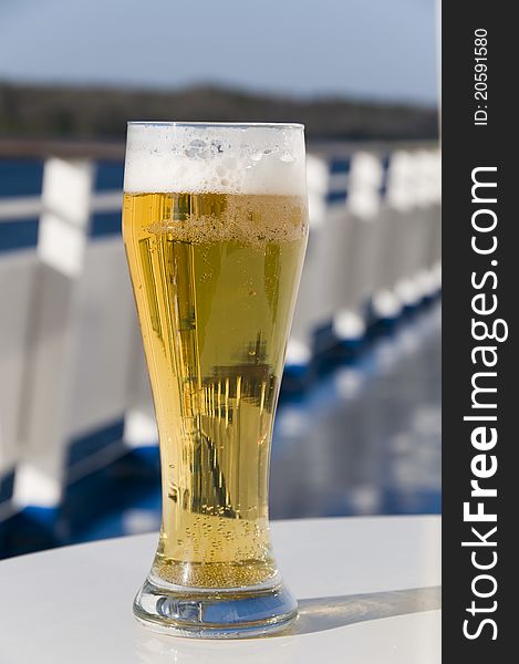 The beer glass costs on a little table on a ship deck