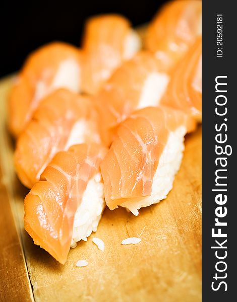 Japanesse inspired food, made with smoked salmon and steamed rice, served in one bite size, on a beige woody background. Japanesse inspired food, made with smoked salmon and steamed rice, served in one bite size, on a beige woody background.