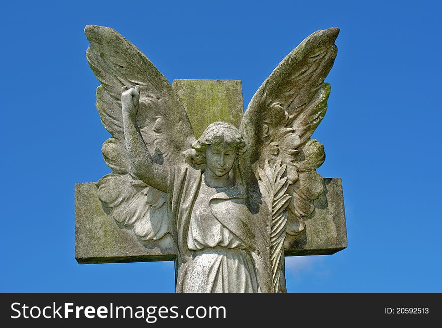 Pre 1900 stone statue of an angel with wings against a bright blue sky with clouds from a grave in the famous landmark Milltown Cemetery Belfast, which is the largest Catholic burial ground in Belfast and synonymous with Irish Republicanism. Pre 1900 stone statue of an angel with wings against a bright blue sky with clouds from a grave in the famous landmark Milltown Cemetery Belfast, which is the largest Catholic burial ground in Belfast and synonymous with Irish Republicanism.