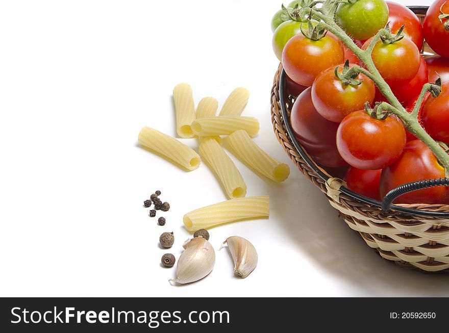 Tomatoes in basket and pasta on white background