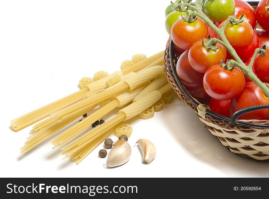 Tomatoes in basket and pasta on white background