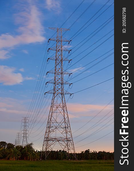 Electricity supply pylons in countryside with blue sky background