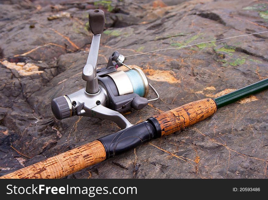 Open-faced spinning reel and rod on the beach rock