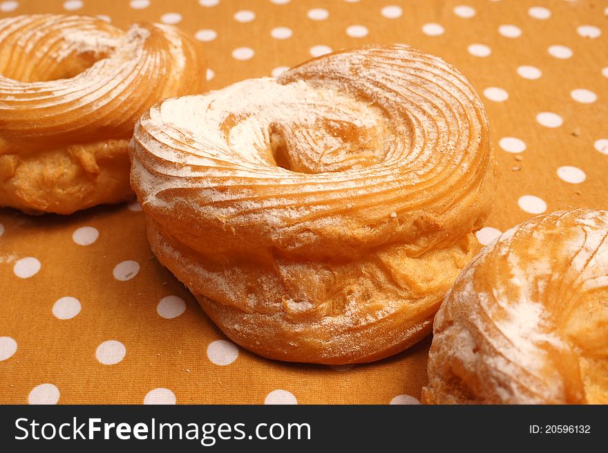 Three doughnuts with sugar on the tablecloth