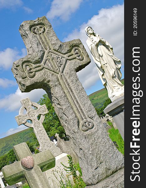 Irish graveyard scene with four very different typical gravestones including granite cross, celtic cross, statue of mary and simple cross with heart in the famous landmark Milltown Cemetery Belfast, which is the largest Catholic burial ground in Belfast and synonymous with Irish Republicanism. Irish graveyard scene with four very different typical gravestones including granite cross, celtic cross, statue of mary and simple cross with heart in the famous landmark Milltown Cemetery Belfast, which is the largest Catholic burial ground in Belfast and synonymous with Irish Republicanism.