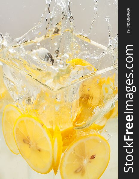 Lemon slices thrown in a transparent bowl causing water-splash. Lemon slices thrown in a transparent bowl causing water-splash