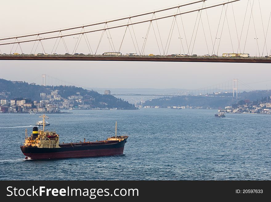 The Bosporus Bridge whcih spans the Bosphorous. Industrial ship passing through straits of Bosphorus... Bosporus Bridge behind, Rumeli Fortress, Fatih Sultan Mehmet Bridge. The Bosporus Bridge whcih spans the Bosphorous. Industrial ship passing through straits of Bosphorus... Bosporus Bridge behind, Rumeli Fortress, Fatih Sultan Mehmet Bridge...