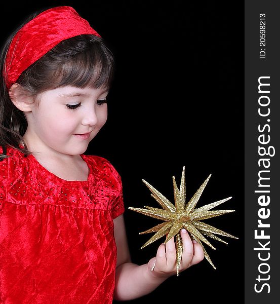 Closeup of pretty girl in christmas dress holding gold star. isolated on black. Closeup of pretty girl in christmas dress holding gold star. isolated on black