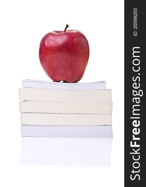 Red apple on the top of a stack of books against a white background