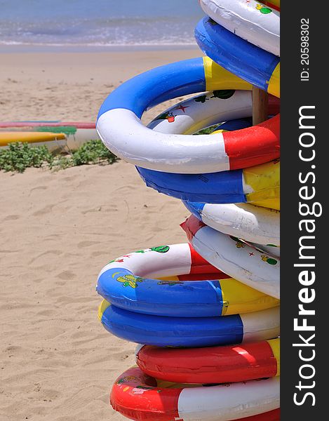 Colorful life buoy and rubber boat on sea sand, shown as sea beach holidy entertainment and various color of rings, water and sand. Colorful life buoy and rubber boat on sea sand, shown as sea beach holidy entertainment and various color of rings, water and sand.