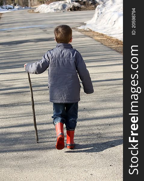 Boy walking opposite direction with walking stick. Boy walking opposite direction with walking stick