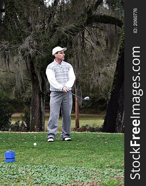 Man studying his drive from the tee box. Man studying his drive from the tee box.