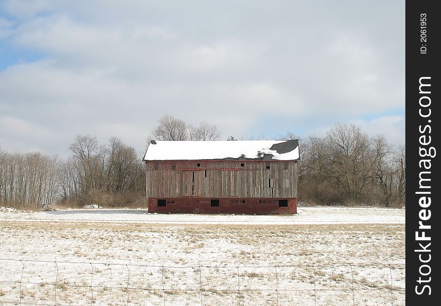 Big wooden barn with snowy roof in snow field