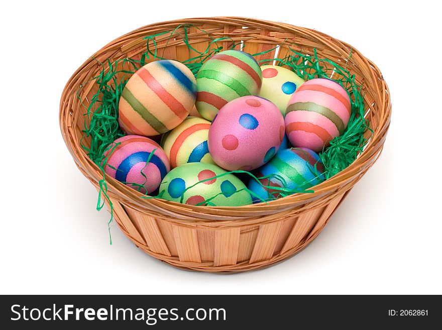 Colorful eggs on green grass in a wooden basket. Isolated on a white background. Colorful eggs on green grass in a wooden basket. Isolated on a white background.