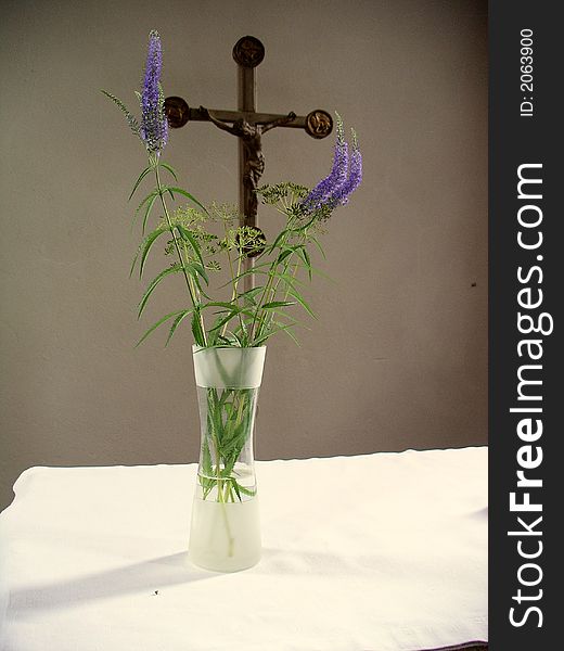 Crucifix behind altar vid flowers in foreground