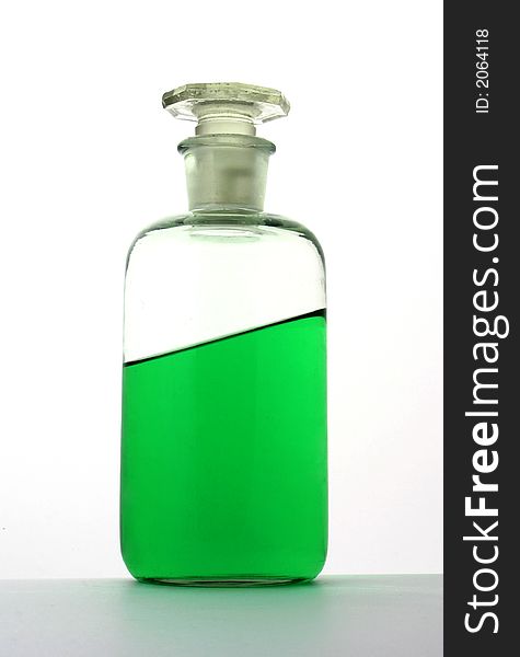 Close up at laboratory bottle filled with tilted green liquid