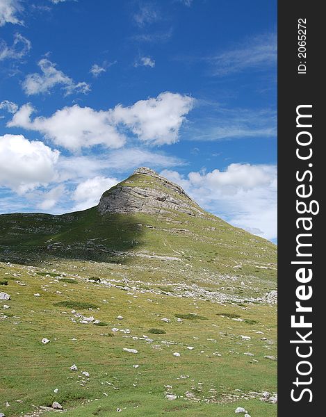 Peak, blue sky, green grass on mountine Durmitor