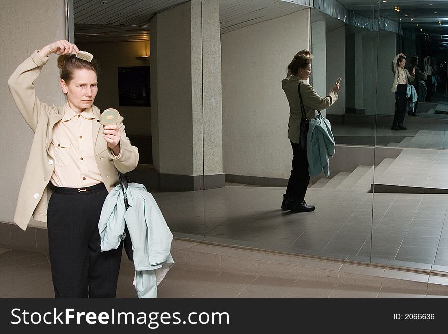 Woman combing out her hair in front of mirror. Woman combing out her hair in front of mirror