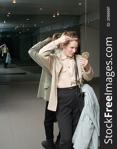 Woman comb her hair in front of mirror