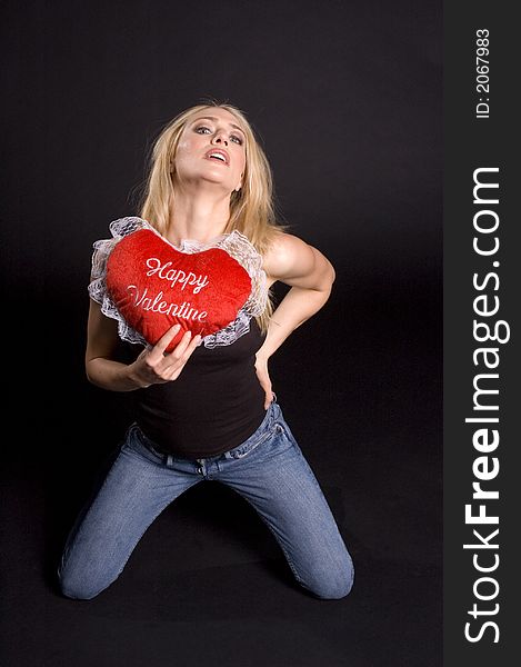 blond woman posing with valentines pillow on a black background. blond woman posing with valentines pillow on a black background