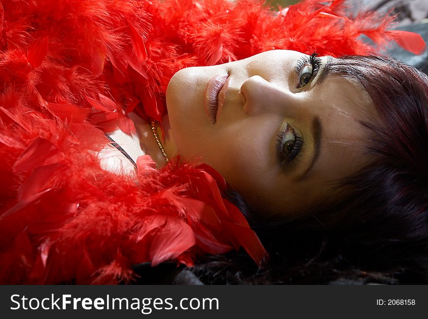 Woman inside plumes. She is lying on bed and looking at camera.