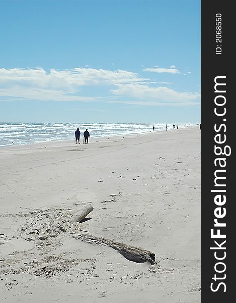 A white sand beach with a blue sky and people on the background