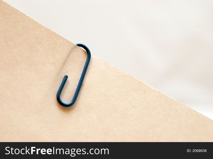 A blue paper clip on a piece of paper. A blue paper clip on a piece of paper