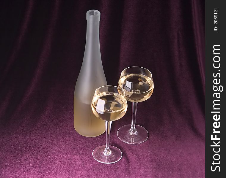 White wine in two glasses and bottle on a claret background