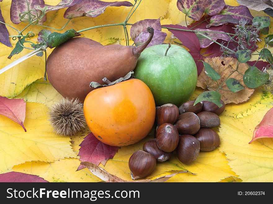 Autumnal fruit composition with green apple , Asian Persimmon (Diospyros kaki), pear and chestnuts on dry leaves. Autumnal fruit composition with green apple , Asian Persimmon (Diospyros kaki), pear and chestnuts on dry leaves