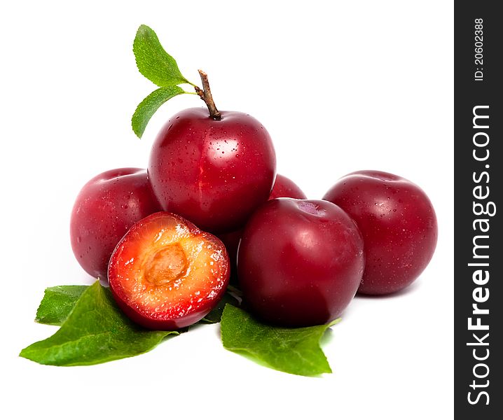 Pile of fresh plums with leafs isolated on white background