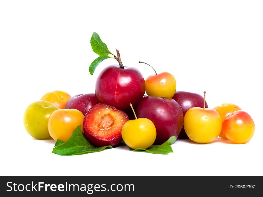 Pile of fresh red and yellow plums with leafs isolated on white background