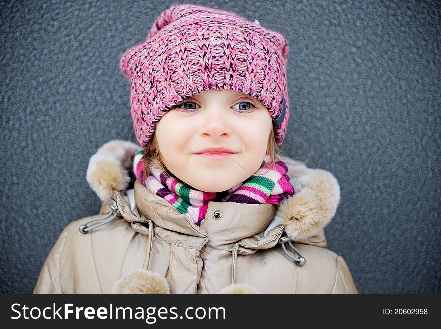 Smiling child girl wearing pink knitted hat and striped scarf. Smiling child girl wearing pink knitted hat and striped scarf