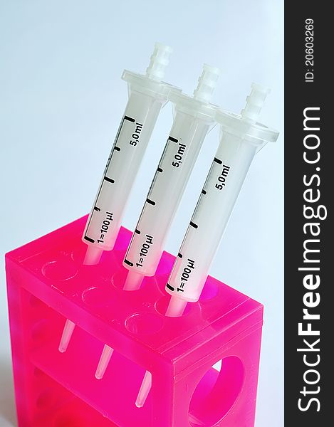 White syringe pipet with pink stand. White syringe pipet with pink stand