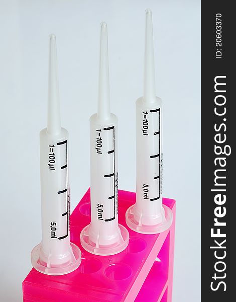 White syringe pipets with pink stand. White syringe pipets with pink stand