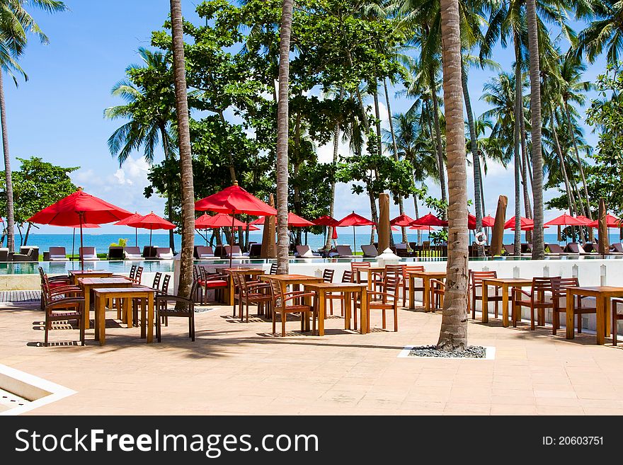 Terrace of a restaurant with red sun shades on a beautiful beach