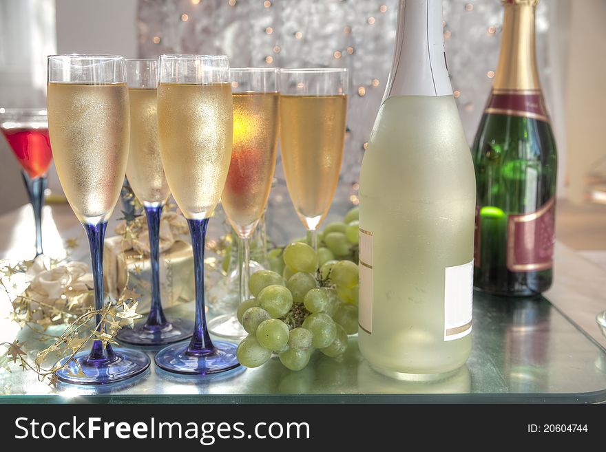 Champagne and wine in glasses,bottles and grapes on silver background with blurred lights. Champagne and wine in glasses,bottles and grapes on silver background with blurred lights.