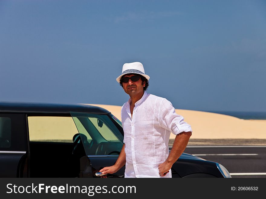 Man in the desert standing close to the car