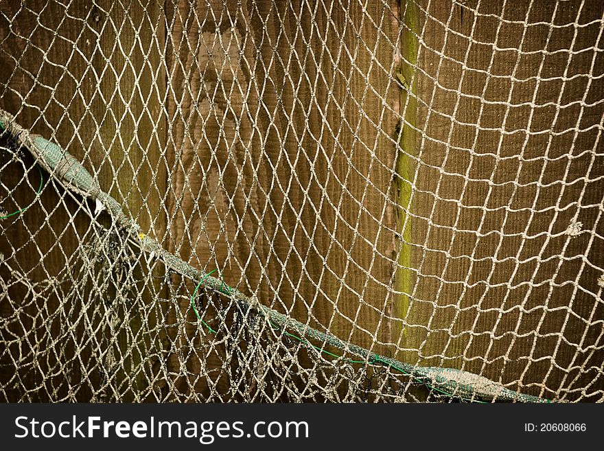 Old shabby fisher net against wooden wall