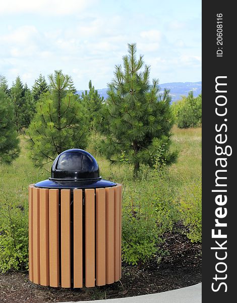 Modern metal and manufactured wood slat garbage can outdoors in a natural landscape park. Modern metal and manufactured wood slat garbage can outdoors in a natural landscape park.