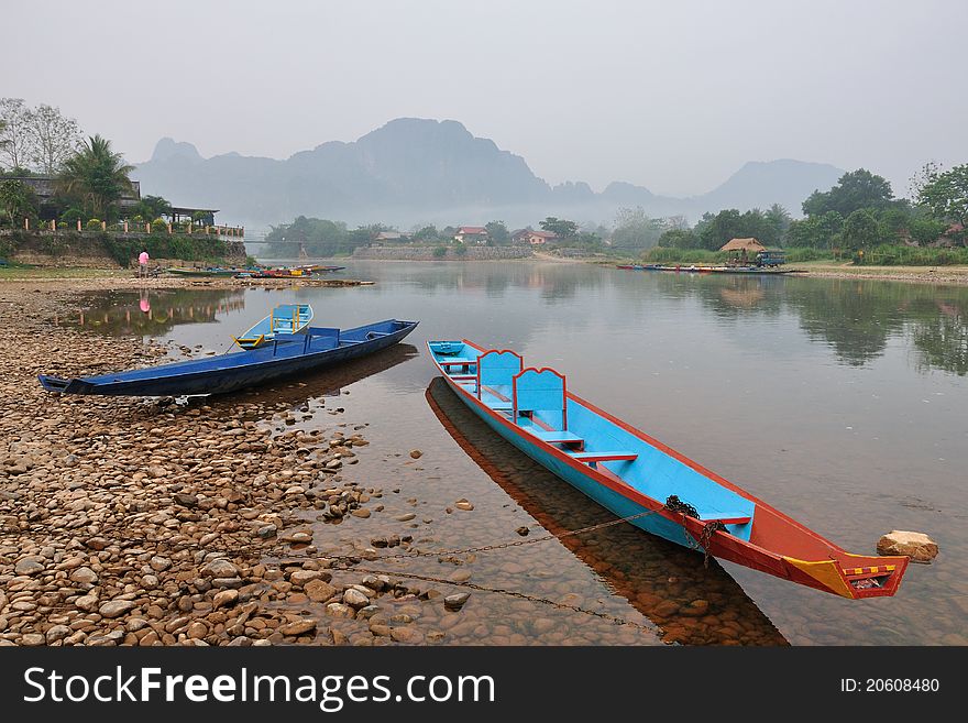 The colorful boats in the shallow river and the mountain on the background. The colorful boats in the shallow river and the mountain on the background