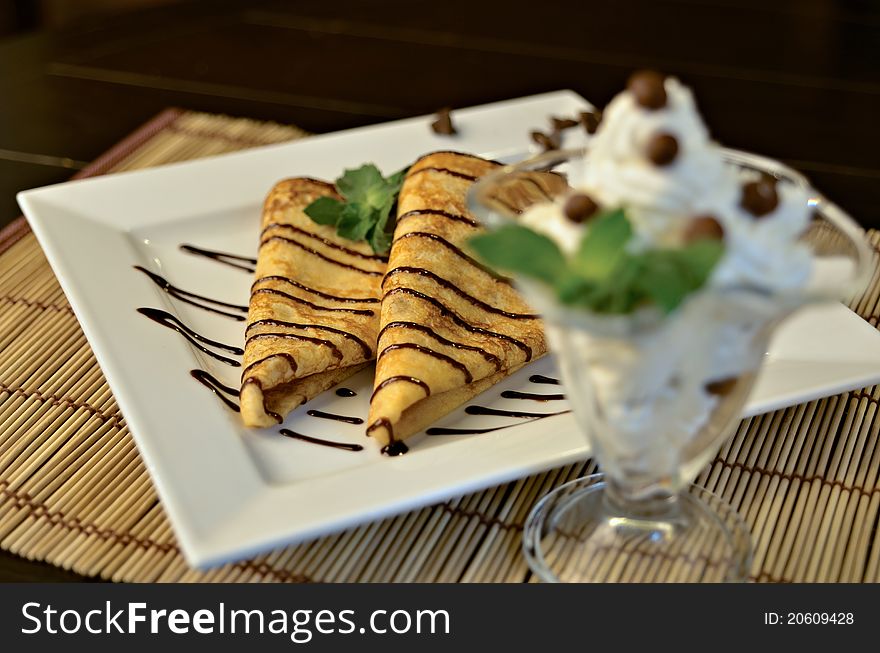 Cream dessert with chocolate balls and mint with pancakes on the background. Cream dessert with chocolate balls and mint with pancakes on the background