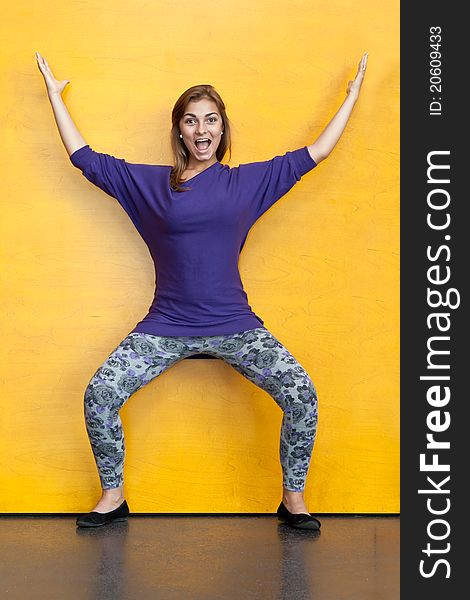 Beautiful girl in purple sweater on a background of yellow wood wall