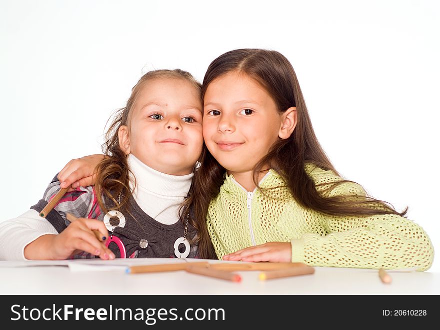 Two happy little girls drawing at table
