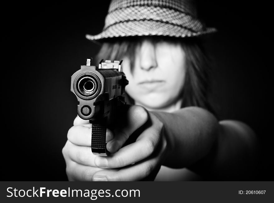 Girl in hat with a big pistol on black background