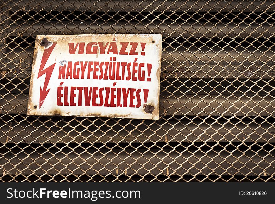 High voltage sign on rusty fence