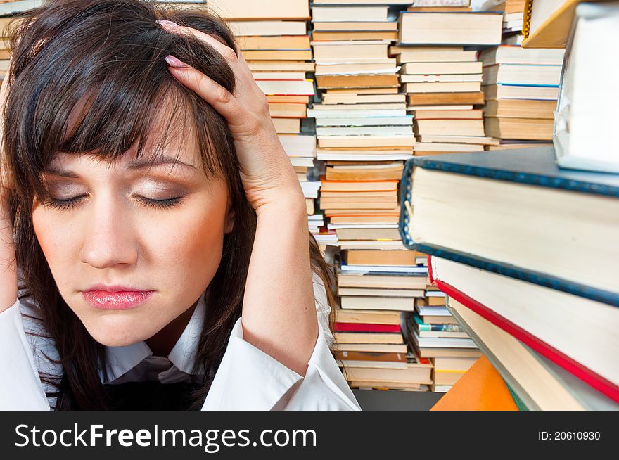 College girl holding her head against many books