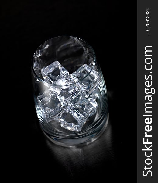 An empty glass on a kitchen bench with ice cubes. An empty glass on a kitchen bench with ice cubes