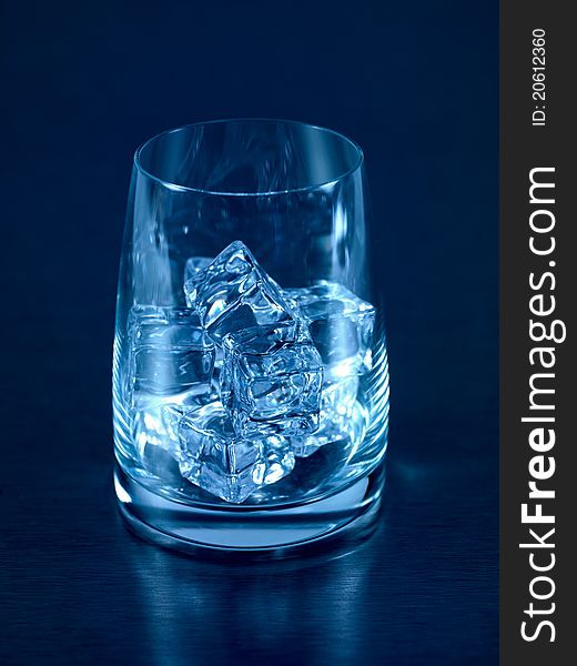 An empty glass on a kitchen bench with ice cubes. An empty glass on a kitchen bench with ice cubes