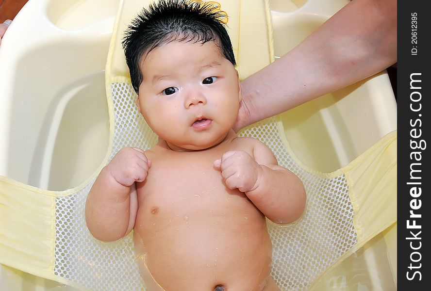 A chinese Baby takes a bath with the help from her mom and father. A chinese Baby takes a bath with the help from her mom and father