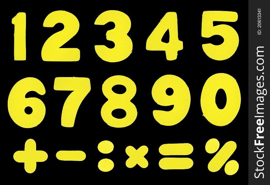 Numbers and mathematic operations simbols made of yellow color sponge-alike soft plastic, isolated on black background